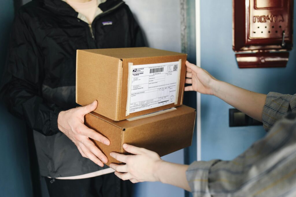 woman handing brown boxes ready to ship to the delivery person